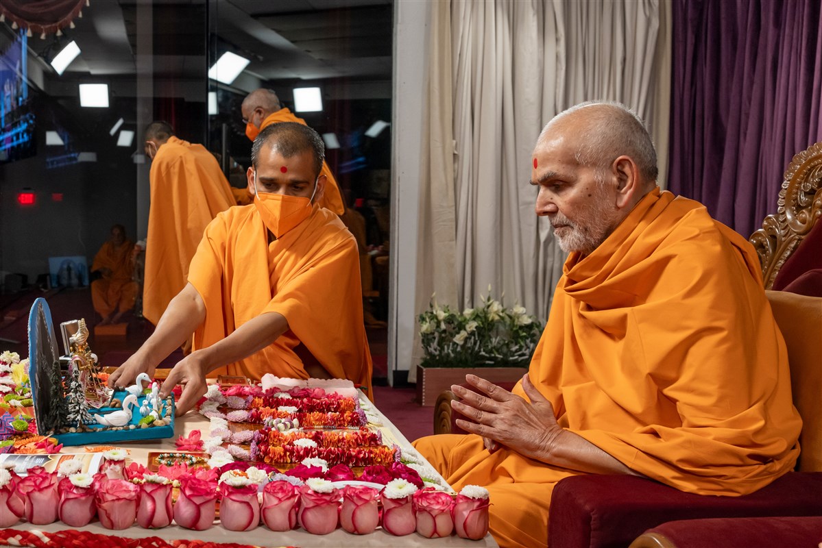 Swamishri adjusts the placement of Shri Harikrishna Maharaj and Shri Gunatitanand Swami Maharaj in his puja