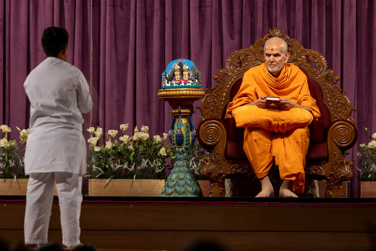 Swamishri attentively listens to a child speaking the sadhana mantra and daily prayer
