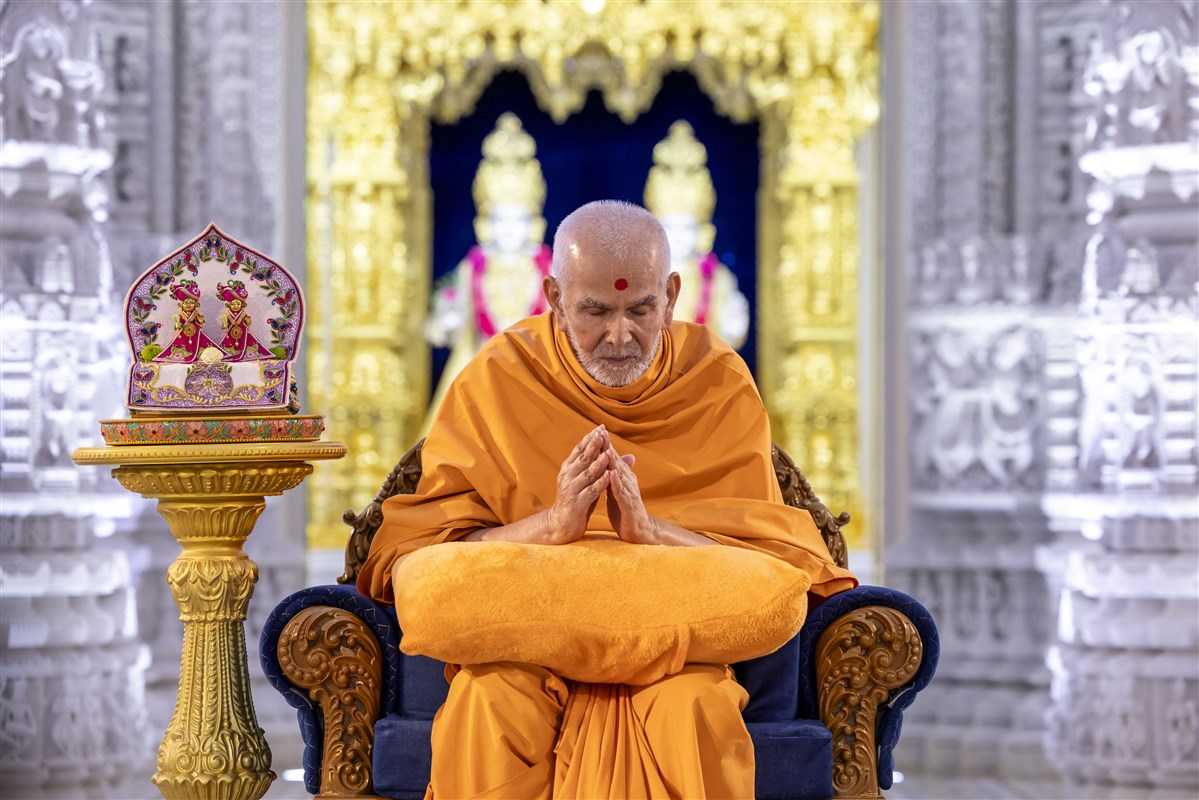 Swamishri humbly bows, his hands folded in reverence