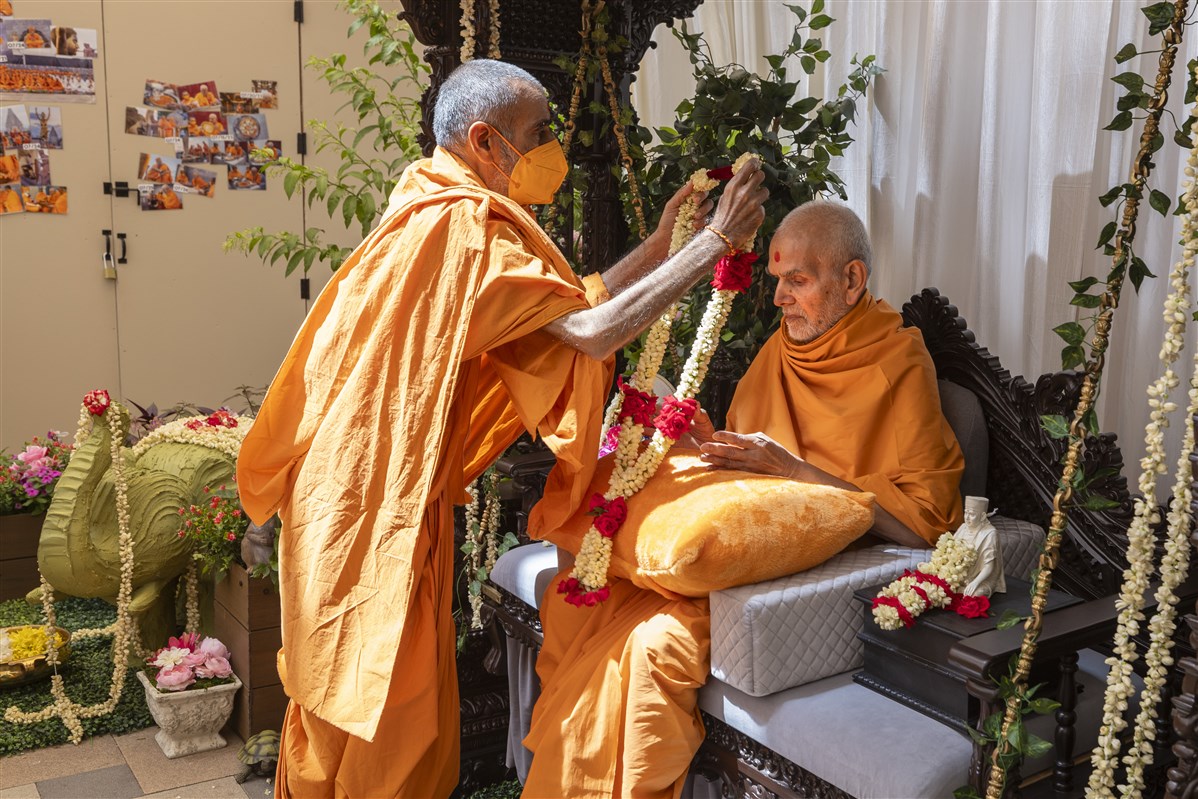 Pujya Anandswarupdas Swami offers a garland to Swamishri