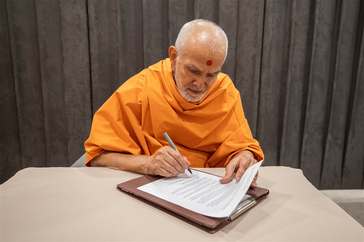 Swamishri signing the congratulatory letter