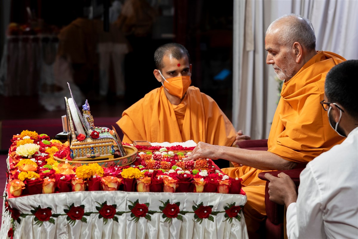 Swamishri adjusts the placement of the murtis in his puja