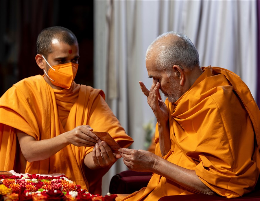 Swamishri reverently touches his eyes after touching the murti