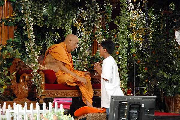 Swamishri attentively listens to a balak who has remained firm in his niyam-dharma 	