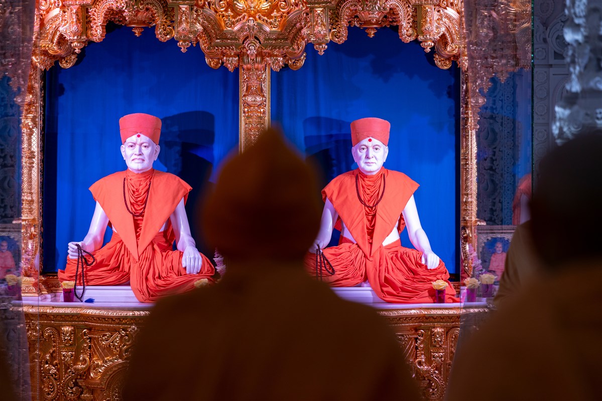 Swamishri engrossed in the darshan of Brahmaswarup Shastriji Maharaj and Brahmaswarup Pramukh Swami Maharaj