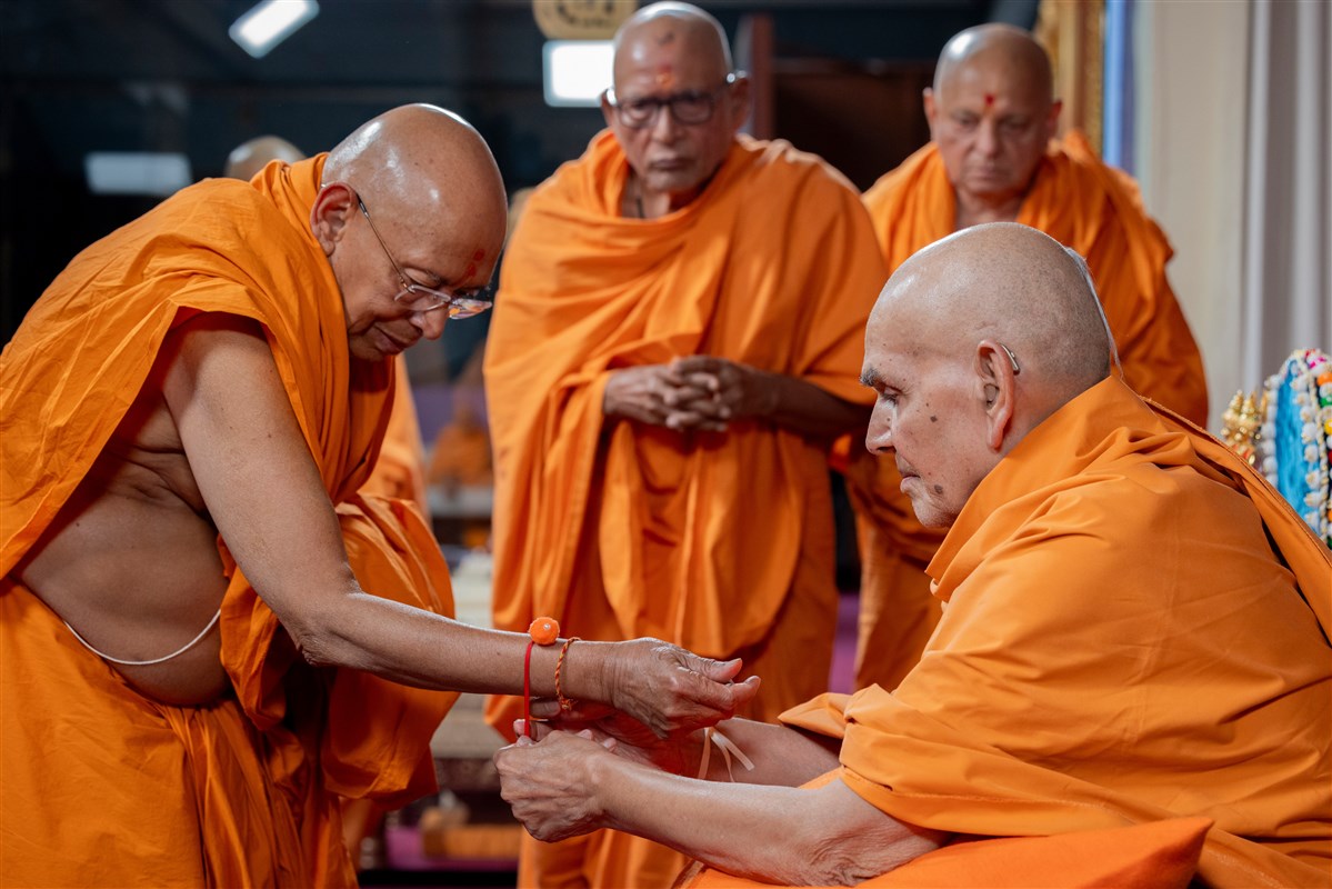 Swamishri ties a rakhi to Sadguru Tyagvallabhdas Swami's wrist