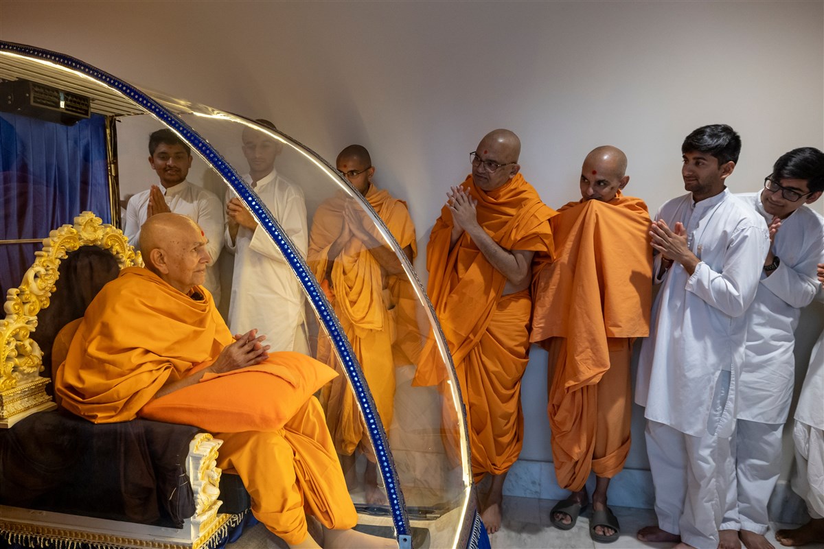 Swamishri greets devotees and swamis with folded hands