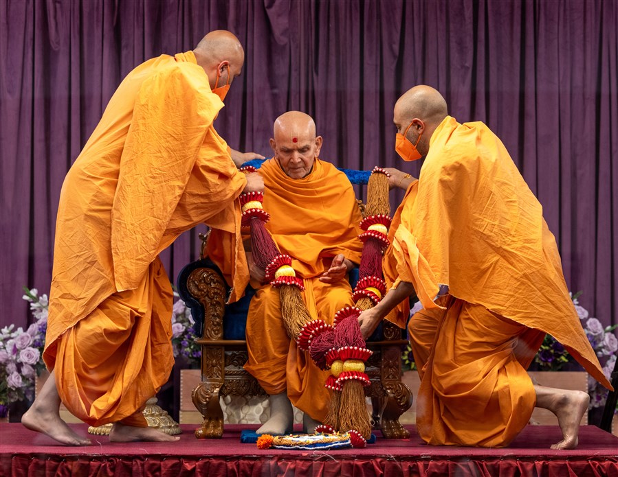 Swamis present Swamishri with a garland