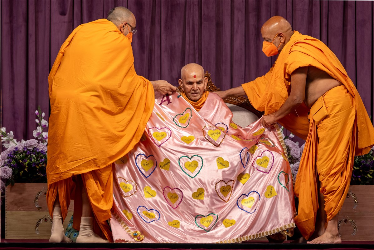 Swamis present a shawl to Swamishri