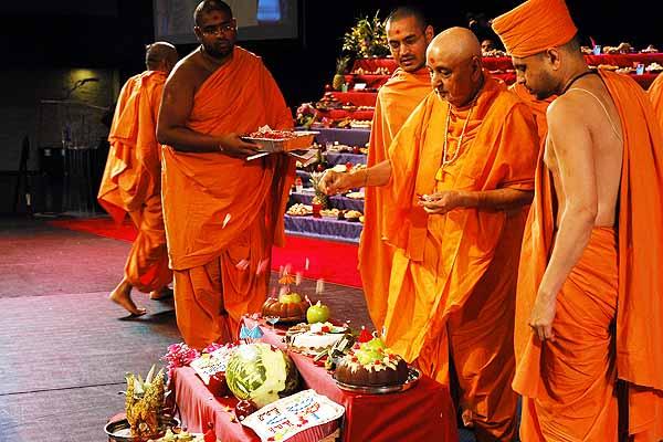 morning ,Swamishri throws flowers on the annakut offering and sanctifies the food items 	