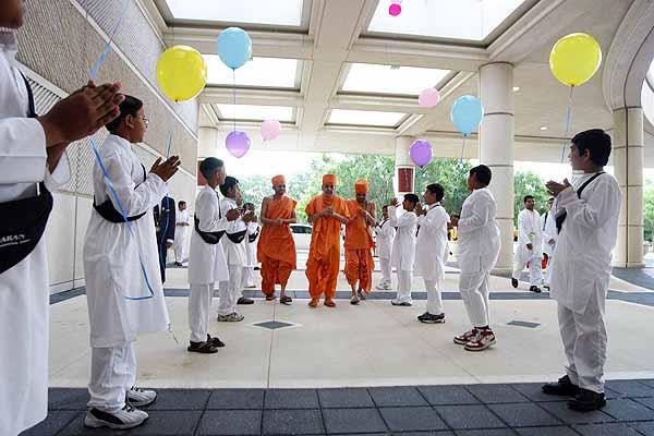 Evening,Balaks greet Swamishri with balloons as he enters the Convention Center