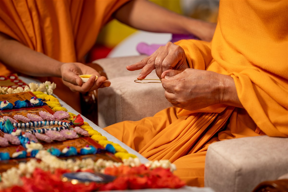 Swamishri applies sandalwood paste for the tilak