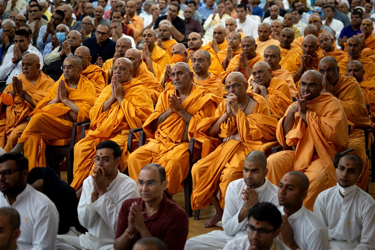 Devotees and swamis greet Swamishri with folded hands