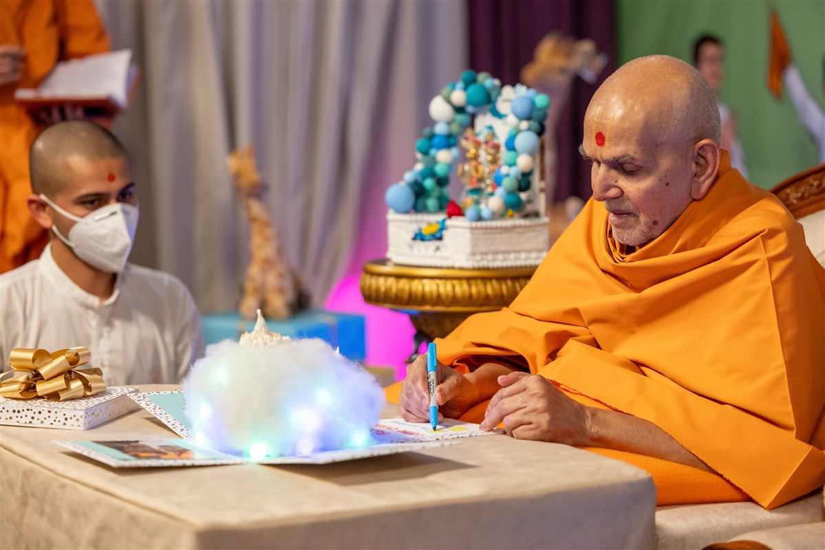 Swamishri signs the invitation card presented to him