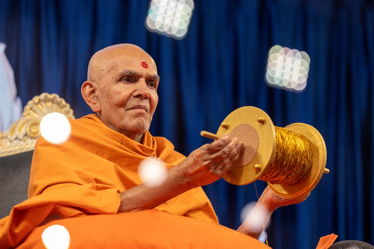 Swamishri holds a kite string as part of an interactive session
