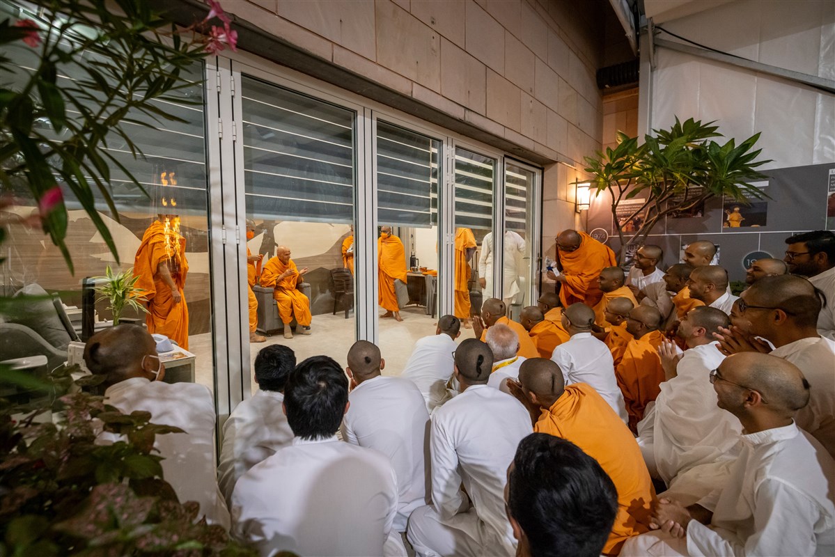Swamis attempt to catch a glimpse of Swamishri before the blinds are lowered