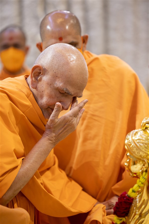Swamishri touches his eyes after touching the feet of Shri Ghanshyam Maharaj in a moment of reverence