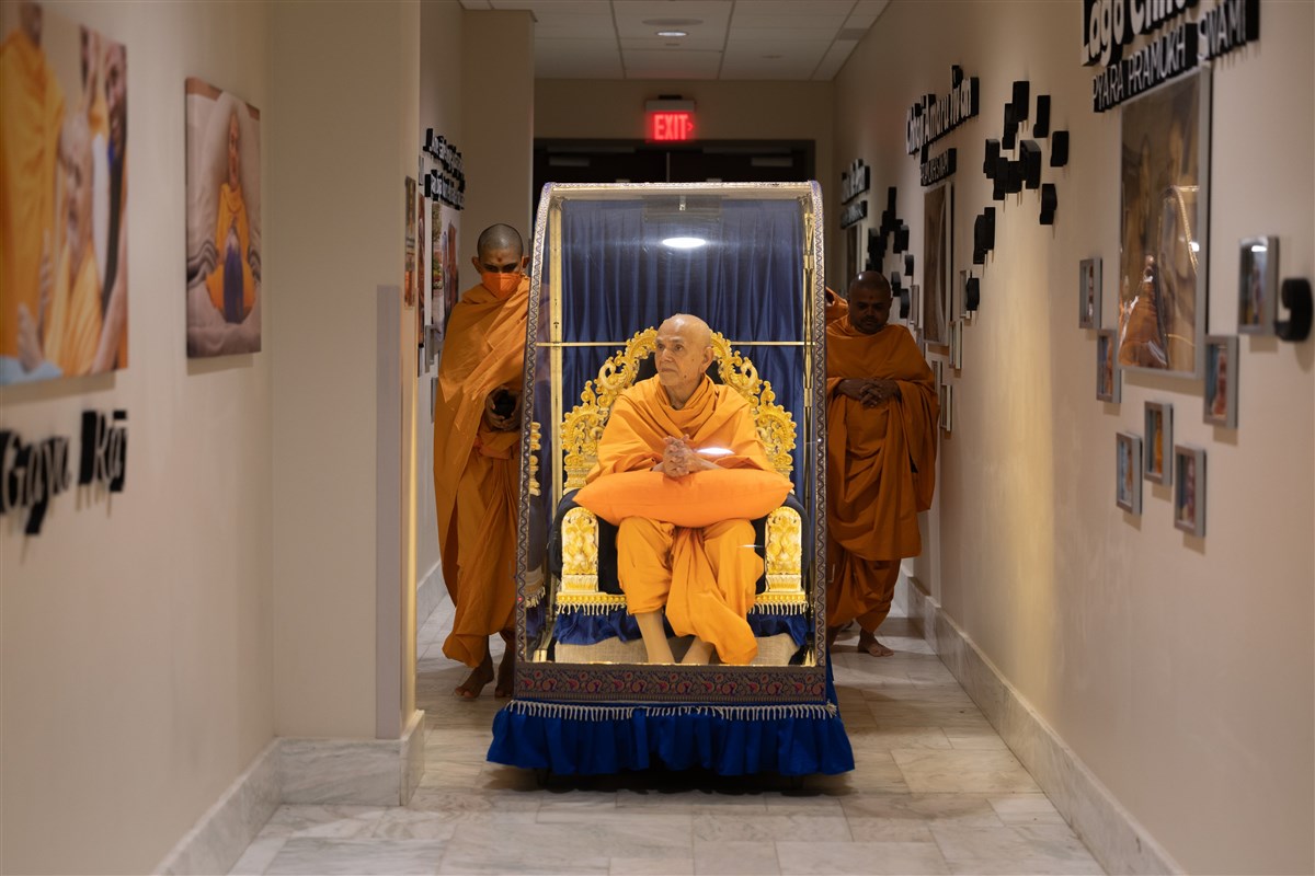 Swamishri views Pramukh Swami Maharaj's photos en route to his daily puja