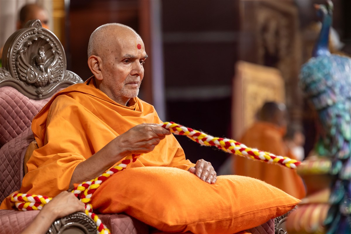 Swamishri lovingly swings Bhagwan Shri Krishna in a traditional hindolo