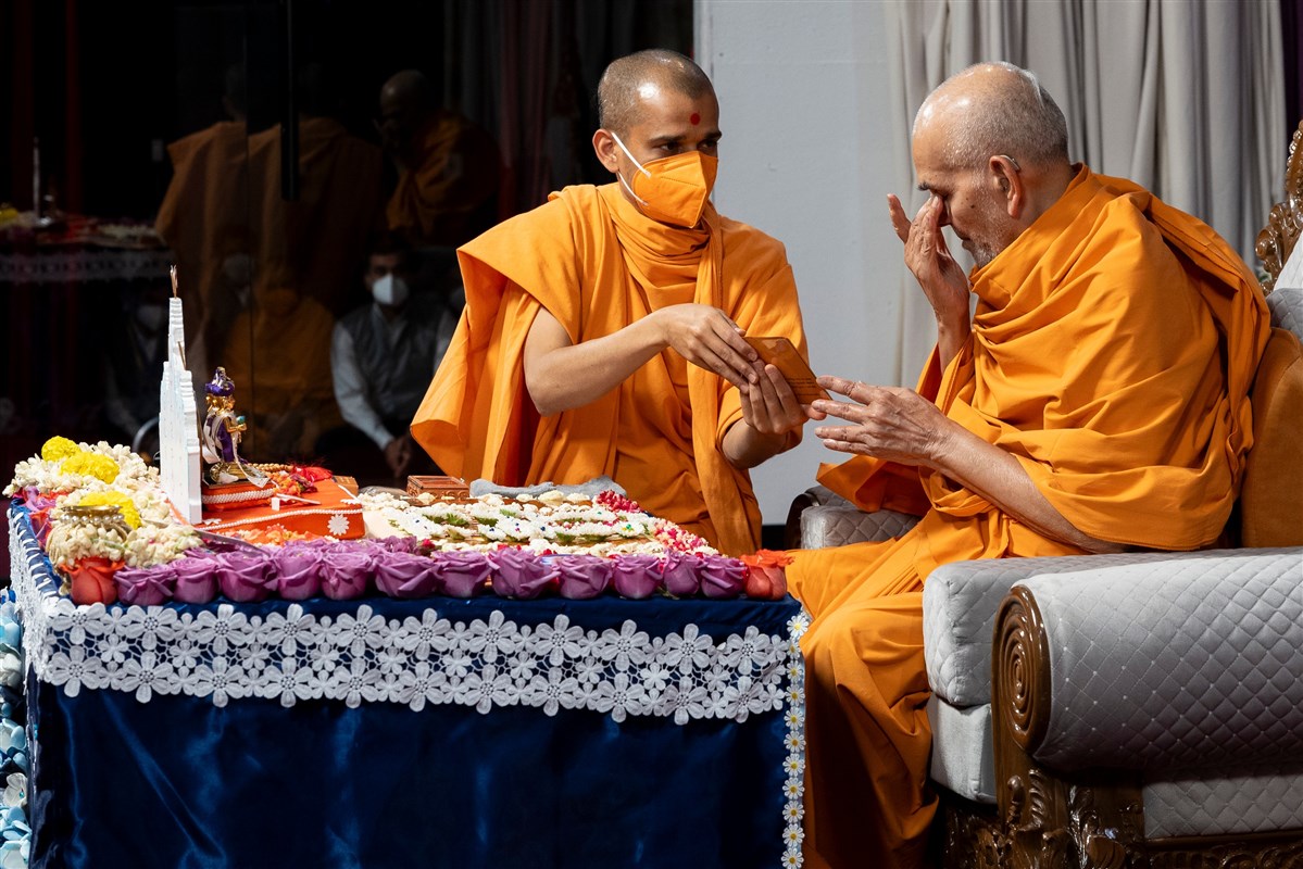 Swamishri touches his eyes after touching the feet of Shri Akshar Purushottam Maharaj in a moment of reverence