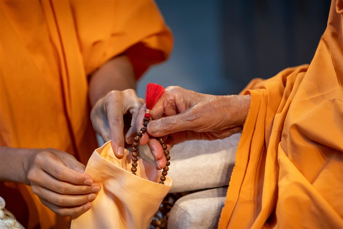 Swamishri picks up the rosary to recite the Swaminarayan mantra