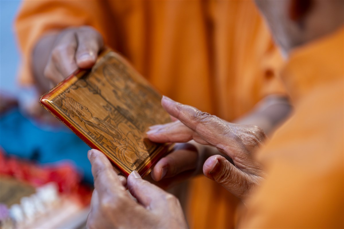 Swamishri touches the feet of Shri Akshar Purushottam Maharaj