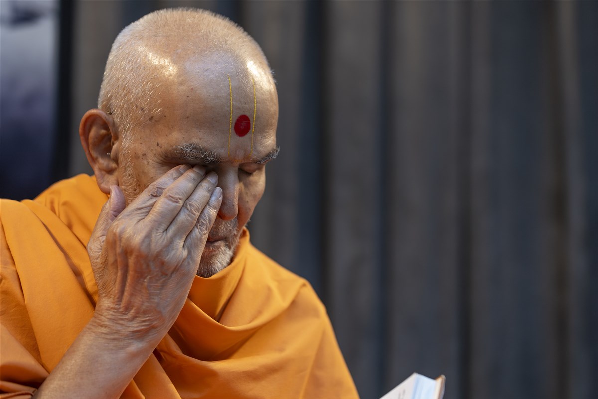 Swamishri reverently touches his eyes after darshan of a murti in the Satsang Diksha scripture