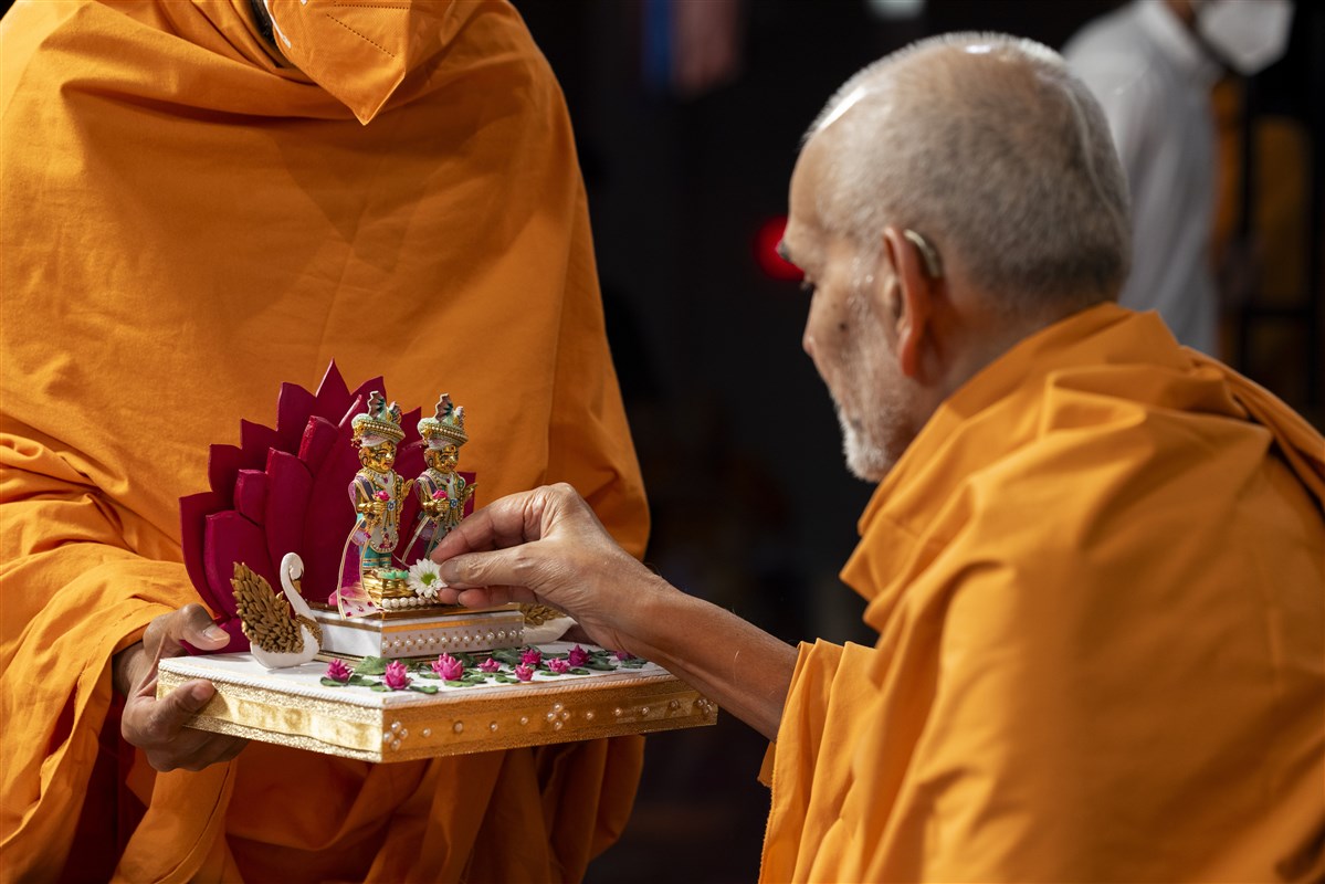 Swamishri offers a flower at the feet of Shri Harikrishna Maharaj and Shri Gunatitanand Swami Maharaj