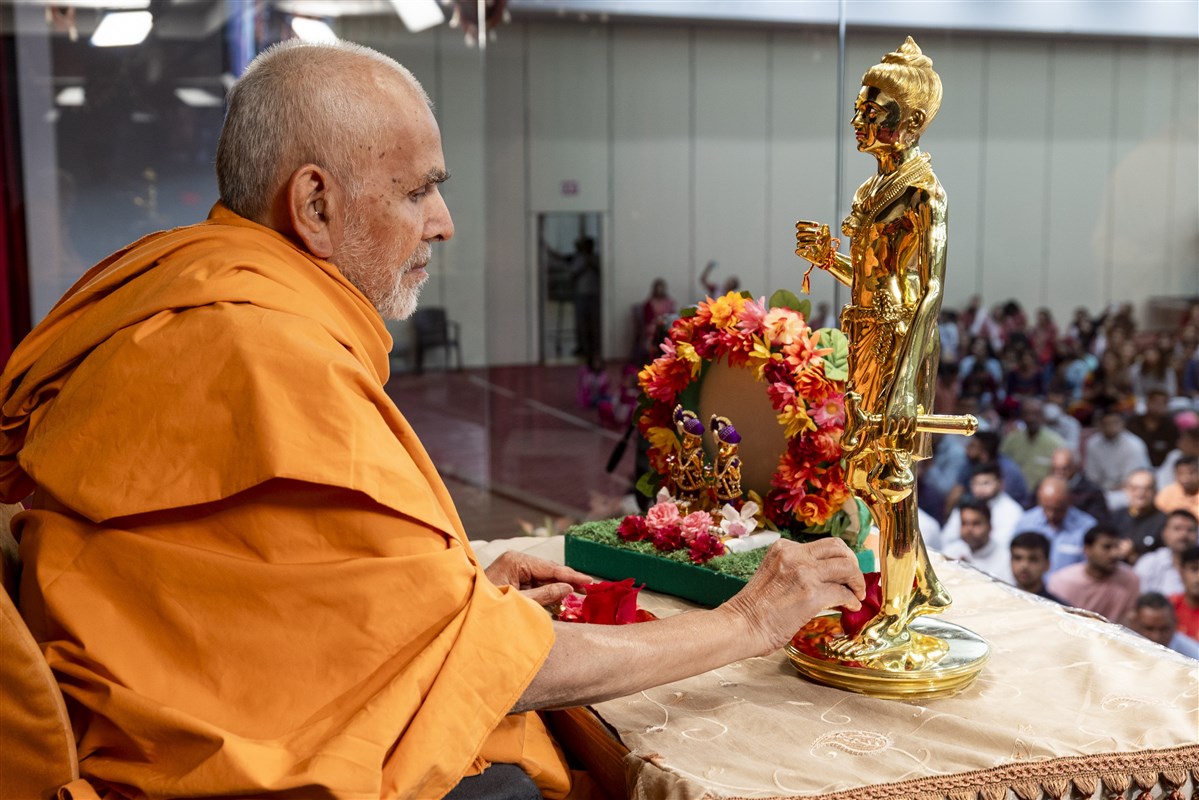 Swamishri offers a flower at the feet of Shri Nilkanth Varni