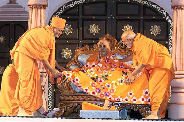 Senior saints present Swamishri with a shawl made by the Mahila Mandal 	