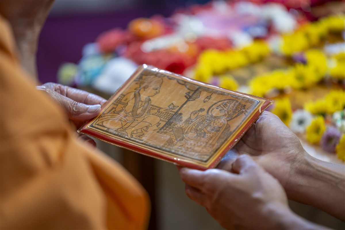 Swamishri reverently touches the holy feet of Shri Akshar Purushottam Maharaj