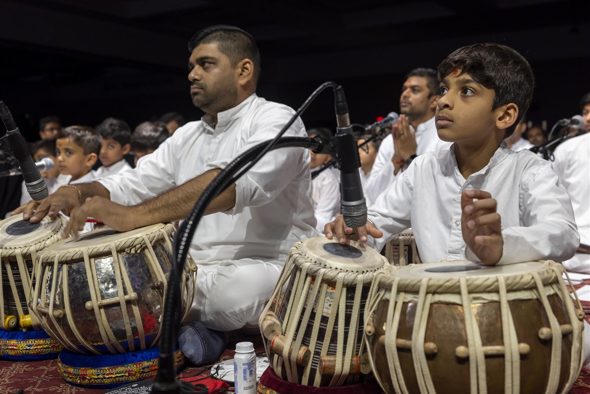 A child and a youth play on the tabla during Swamishri’s puja