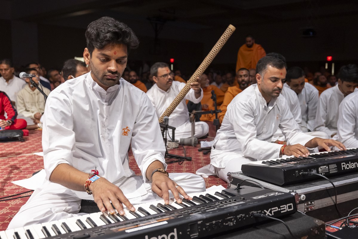 Youths play musical tunes as Swamishri greets devotees