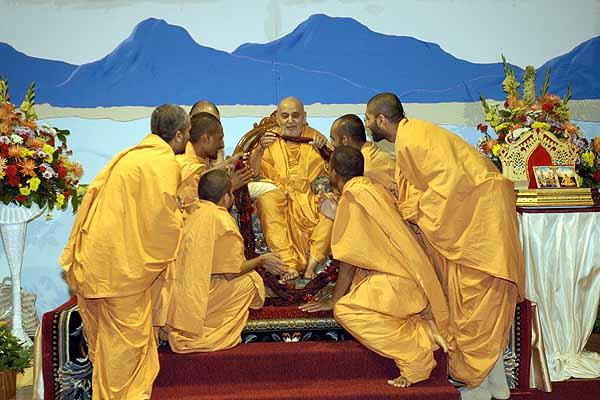 Saints offer a garland to Swamishri 