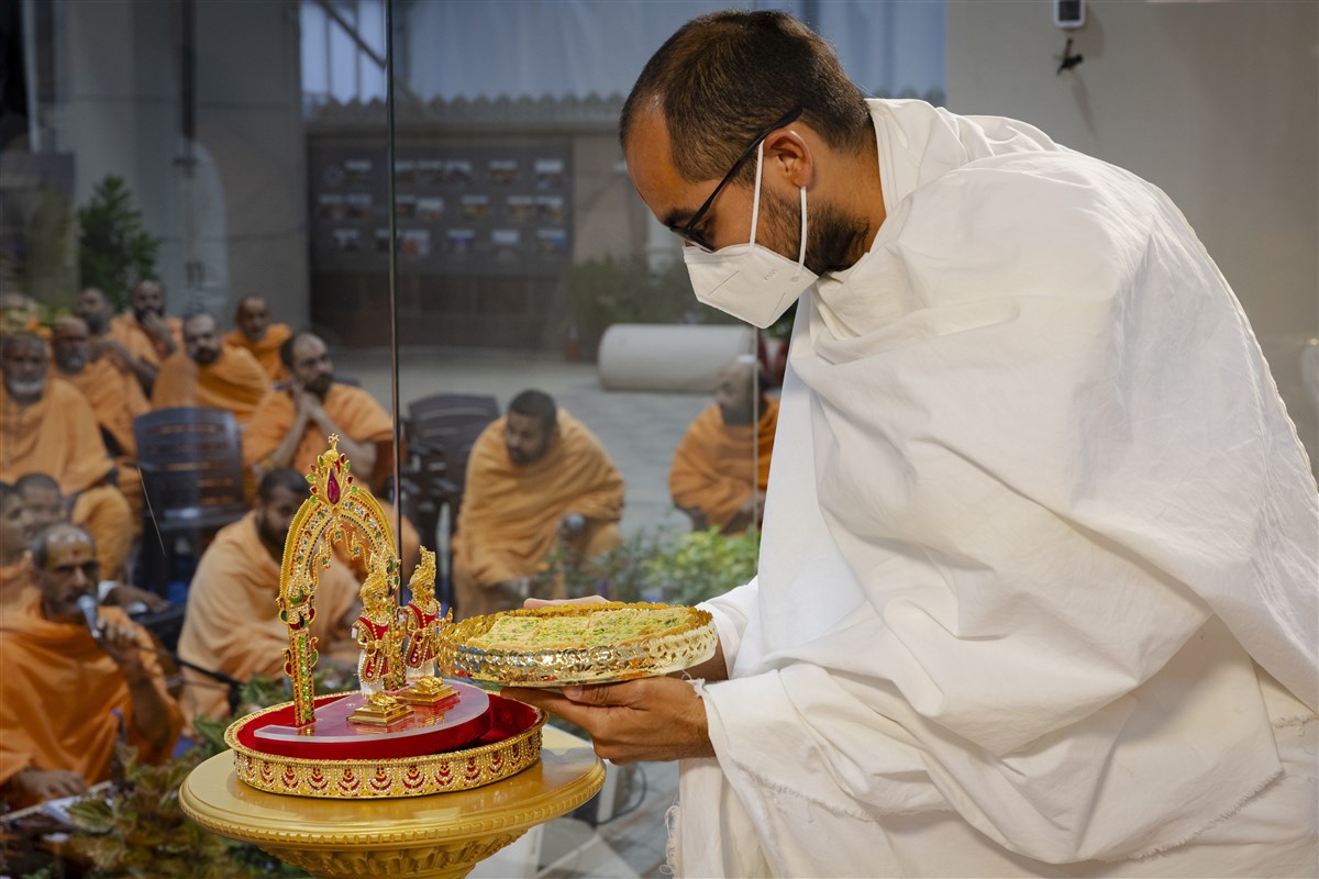 A parshad offers thal to Shri Harikrishna Maharaj and Shri Gunatitanand Swami Maharaj