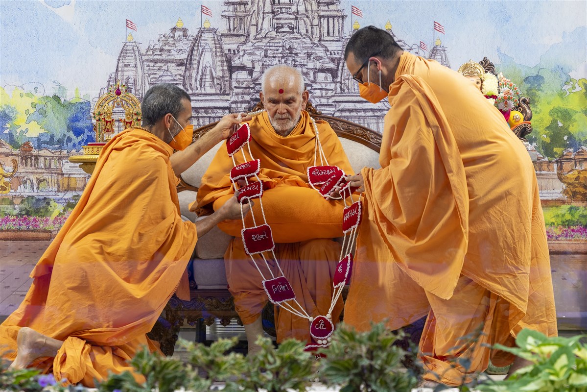 Swamis present a garland to Swamishri