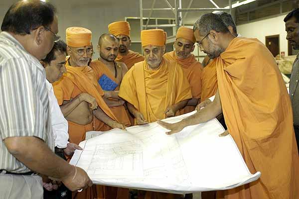 Balika Din, July 16, 2004 -  Swamishri studies the architectural plans for BAPS