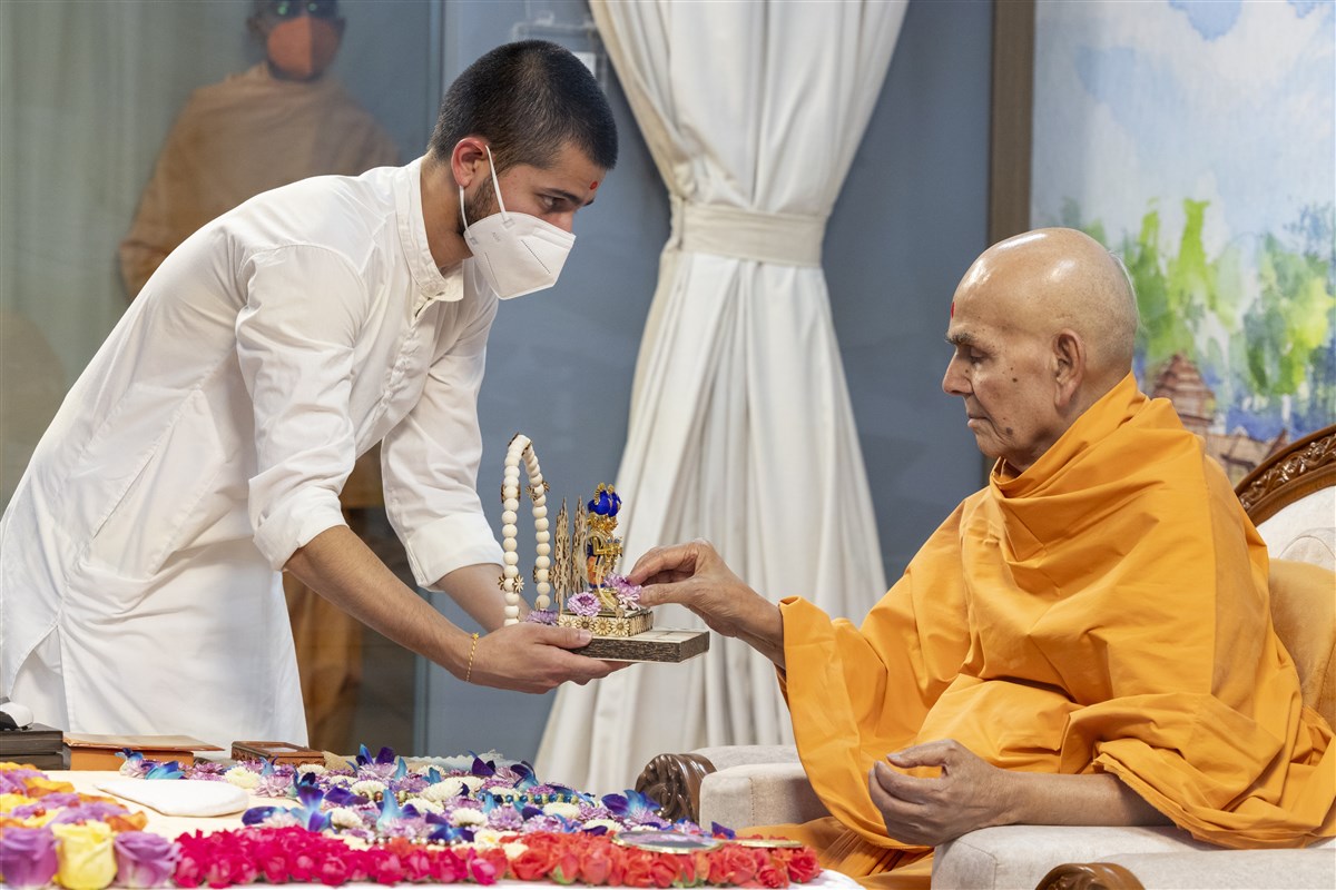 A flower is offered to Shri Harikrishna Maharaj and Shri Gunatitanand Swami Maharaj