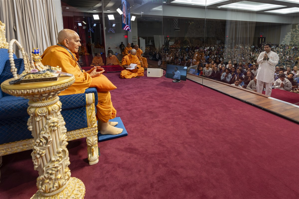 Swamishri interacts with volunteers during the evening assembly