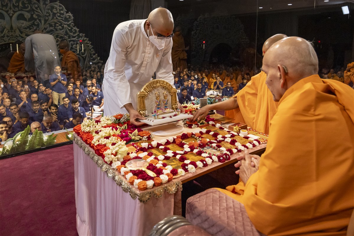 Swamishri adjusts the placement of Shri Harikrishna Maharaj and Shri Gunatitanand Swami Maharaj in his puja