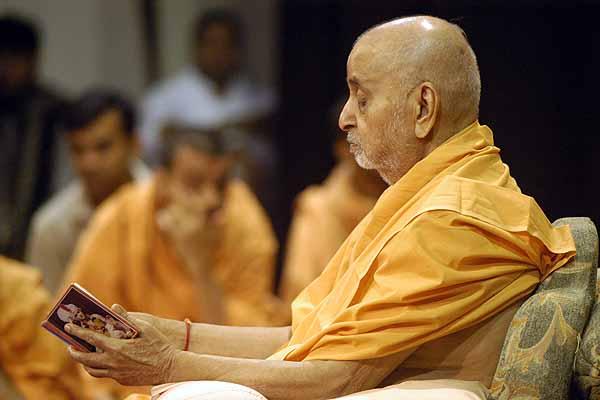 Swamishri carefully reads verses from the Shikshapatri