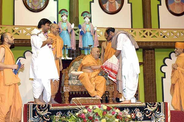 Swamishri is greeted by Sant Shri Rameshbhai Oza and Shri Bhagwatbhai 