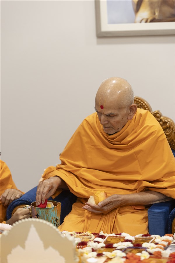 Swamishri adds flowers to the sanctified water