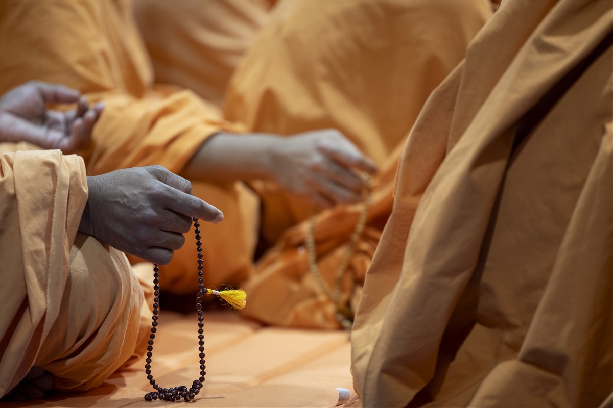 Swamis turn the mala while engrossed in puja darshan
