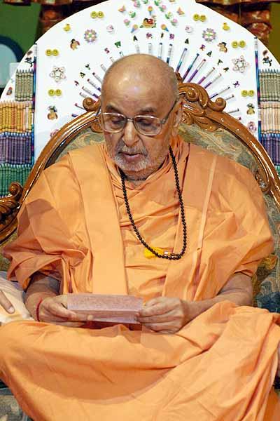 Swamishri reads letters during the evening assembly 