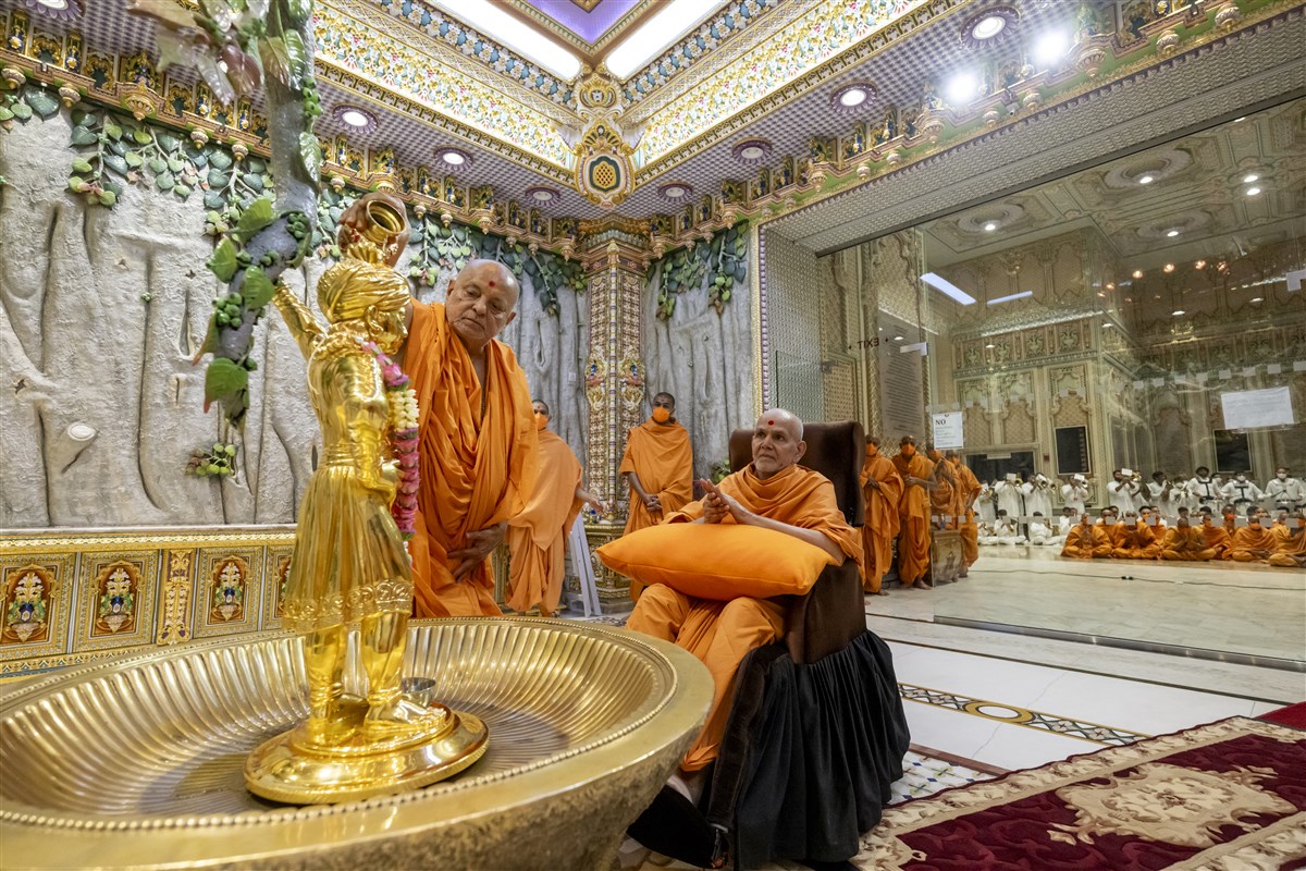 Swamishri engrossed in darshan while Sadguru Pujya Ishwarcharandas Swami performs the abhishek of Shri Ghanshyam Maharaj