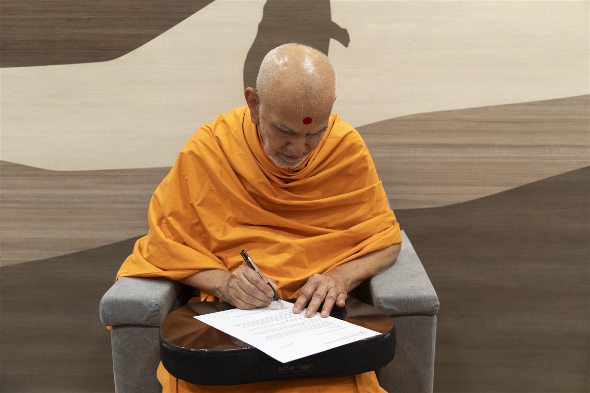 Swamishri writing a letter for the United Nations delegation visiting Akshardham