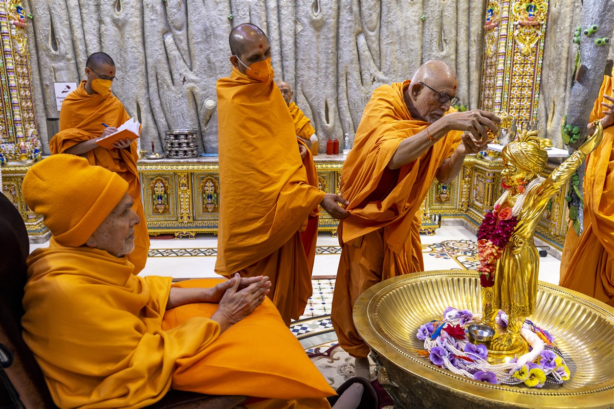 Swamishri engrossed in darshan as Sadguru Pujya Bhaktipriyadas Swami performs the abhishek of Shri Ghanshyam Maharaj