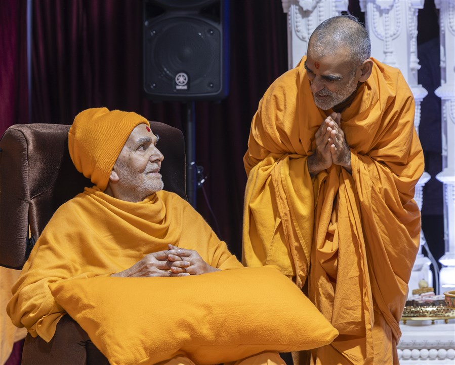 Pujya Anandswarupdas Swami greets Swamishri with folded hands