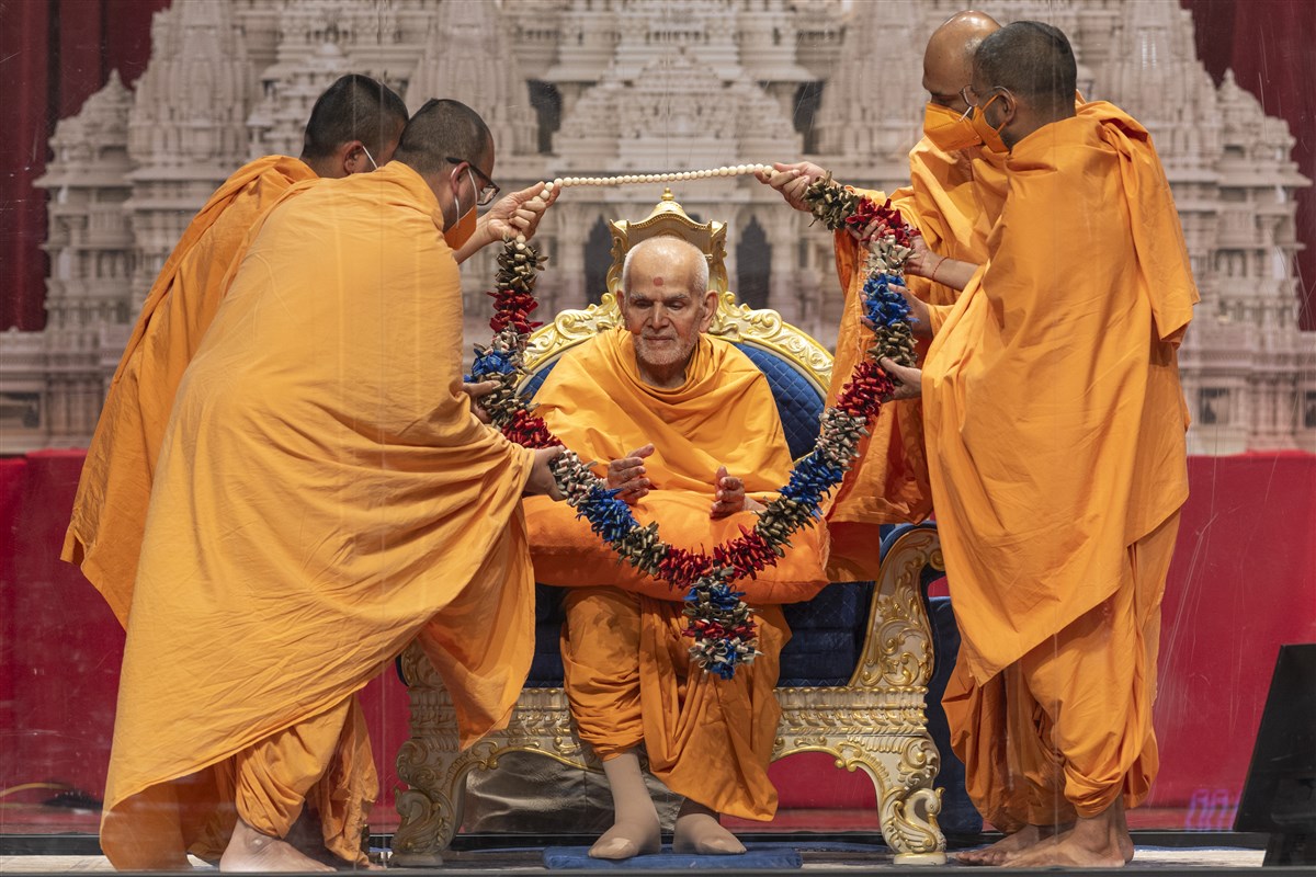 Swamis present a garland to Swamishri